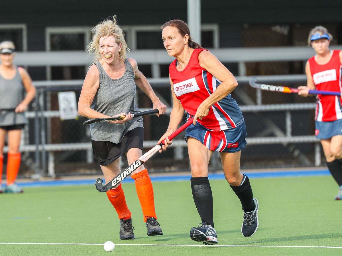 Masters woman running to hit hockey ball