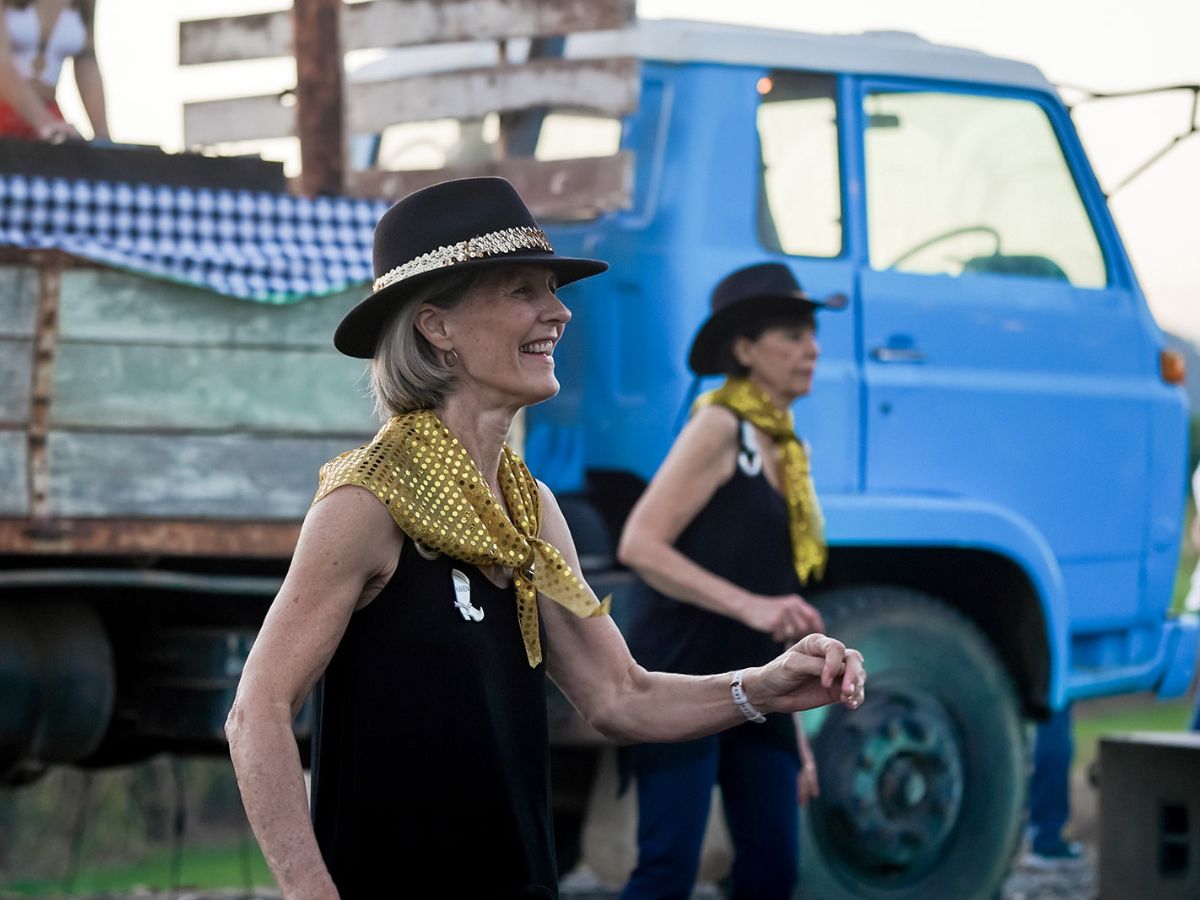 Two ladies wearing country hats dancing at a social event