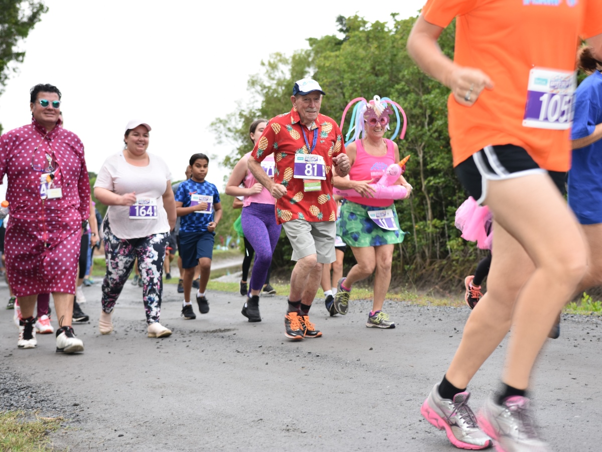 Group of people dressed in bright colours running and walking in charity run