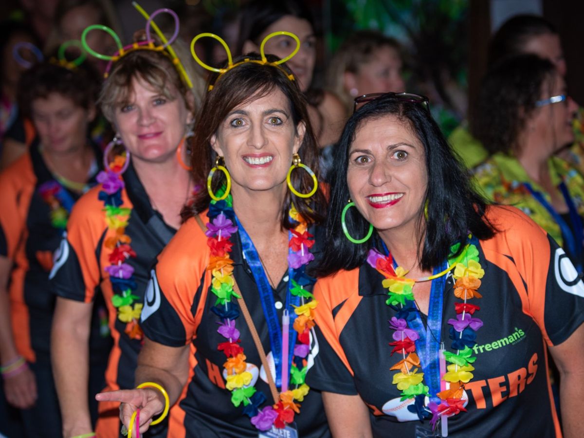 Group of females wearing tropical costumes posing for a photo at a social event