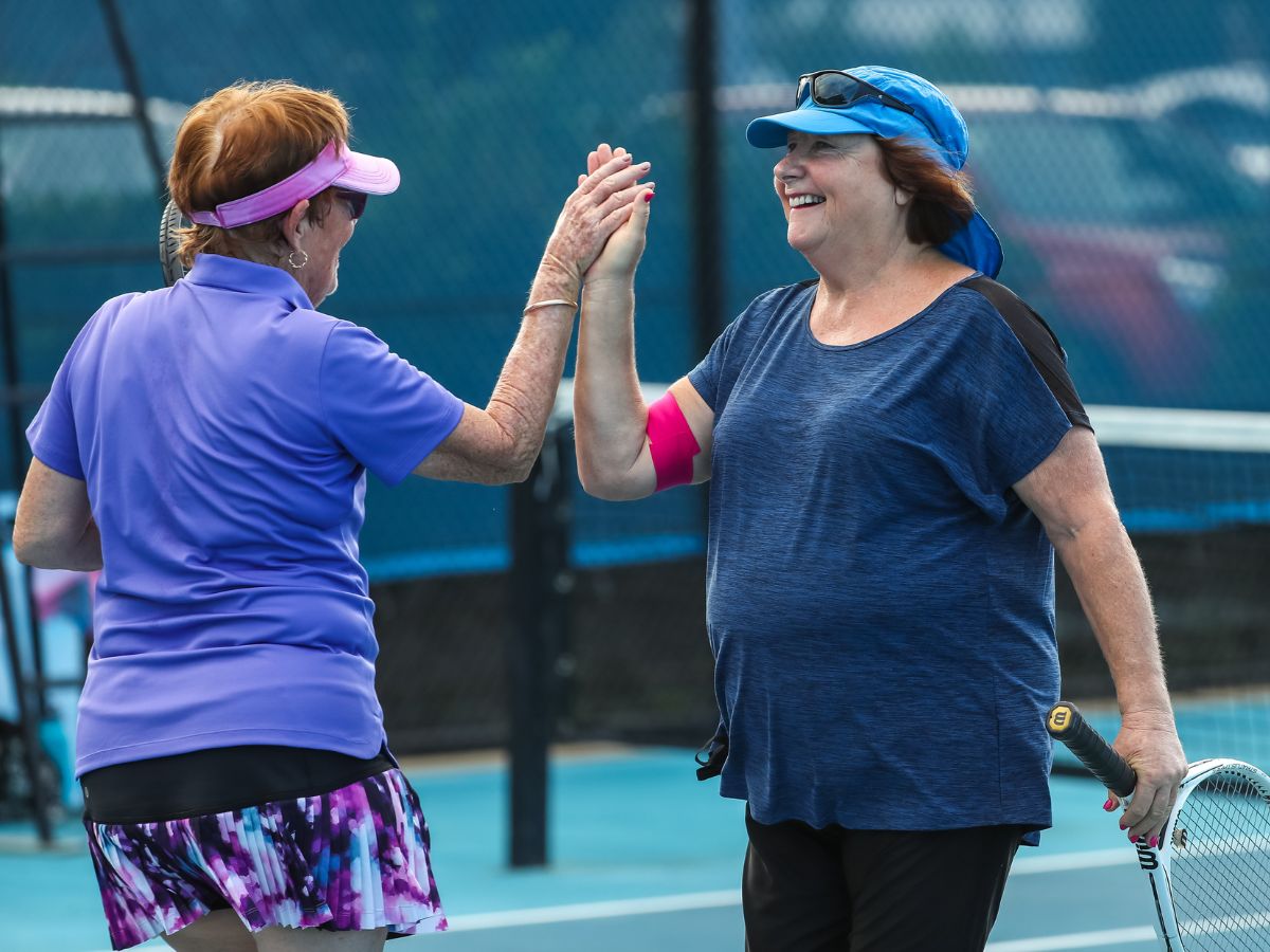 Female tennis competitors hi-fiving
